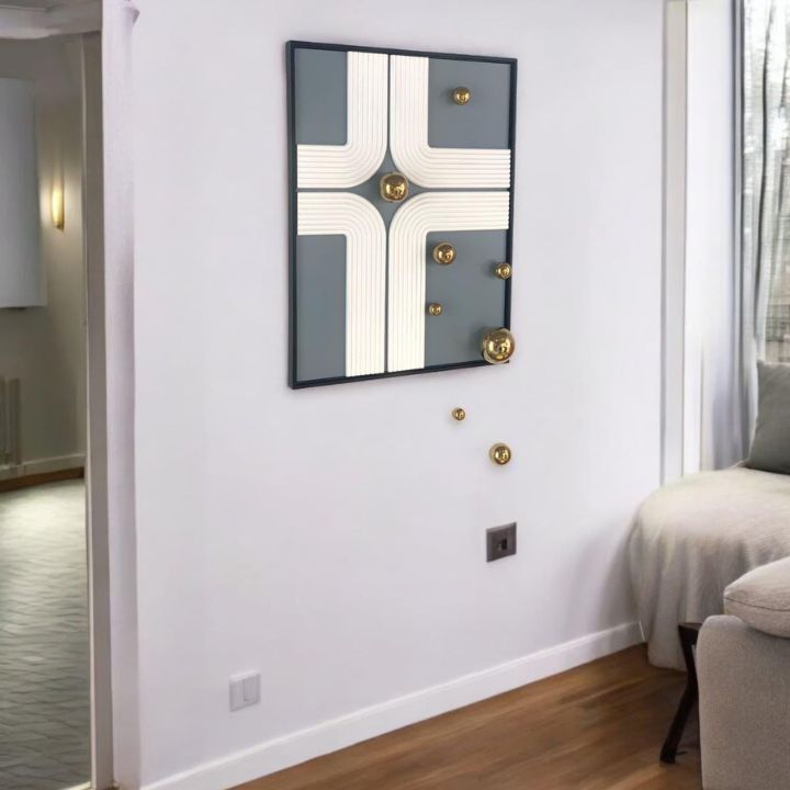 Decorative mirror with geometric design on a white wall in a room.