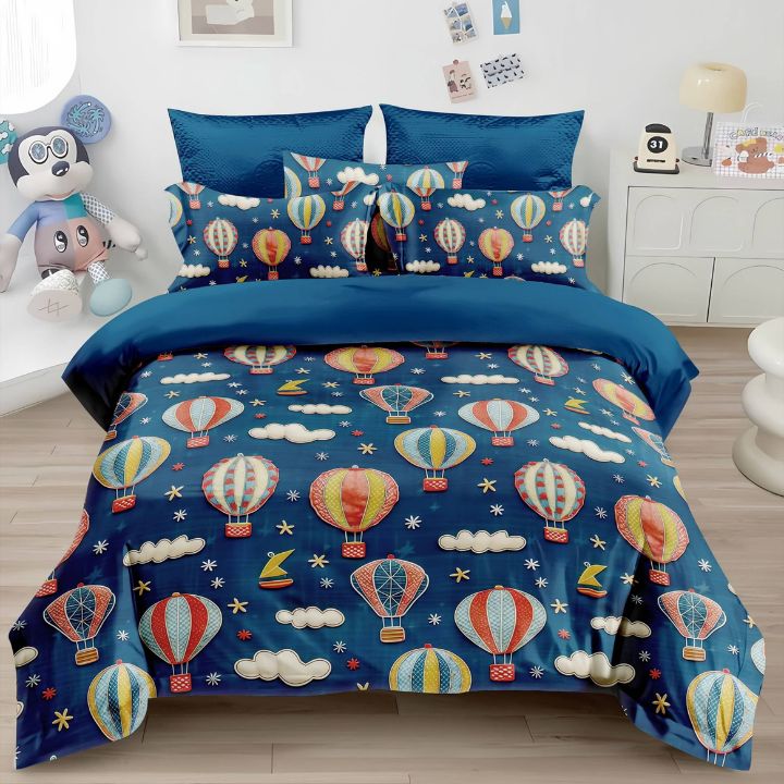 Blue bedding set with hot air balloon pattern on a bed in a room.