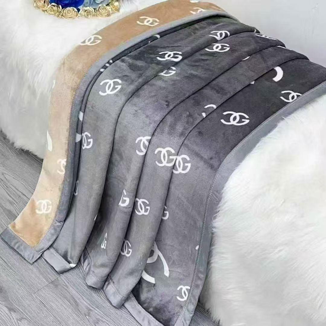 Gray blanket with white logos draped over a white surface