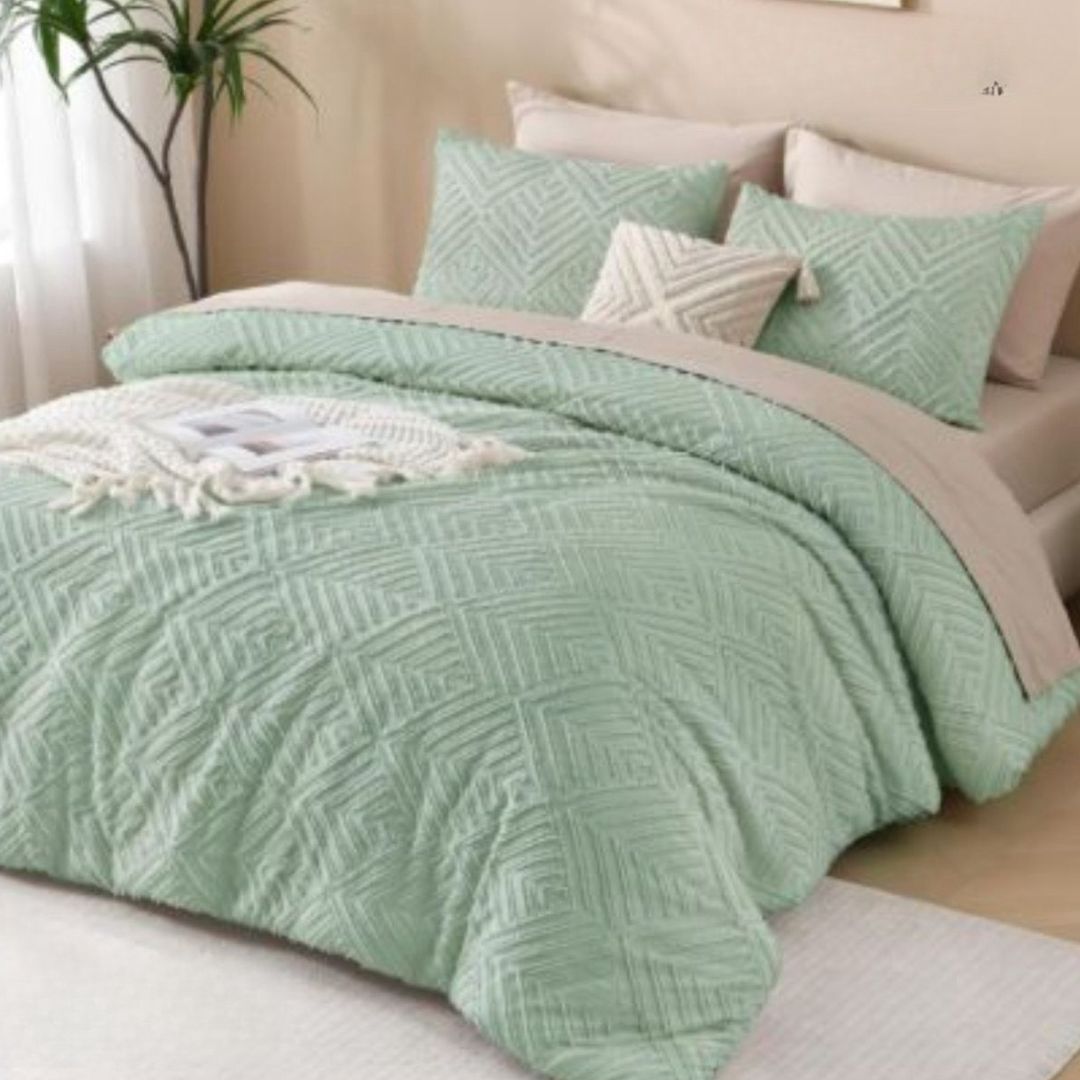 Green textured quilt and pillow set on a bed with a neutral background