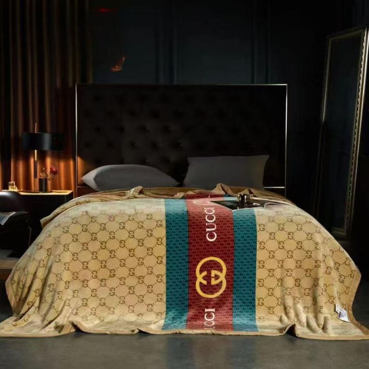 Bed with a Gucci-themed comforter in a dimly lit room