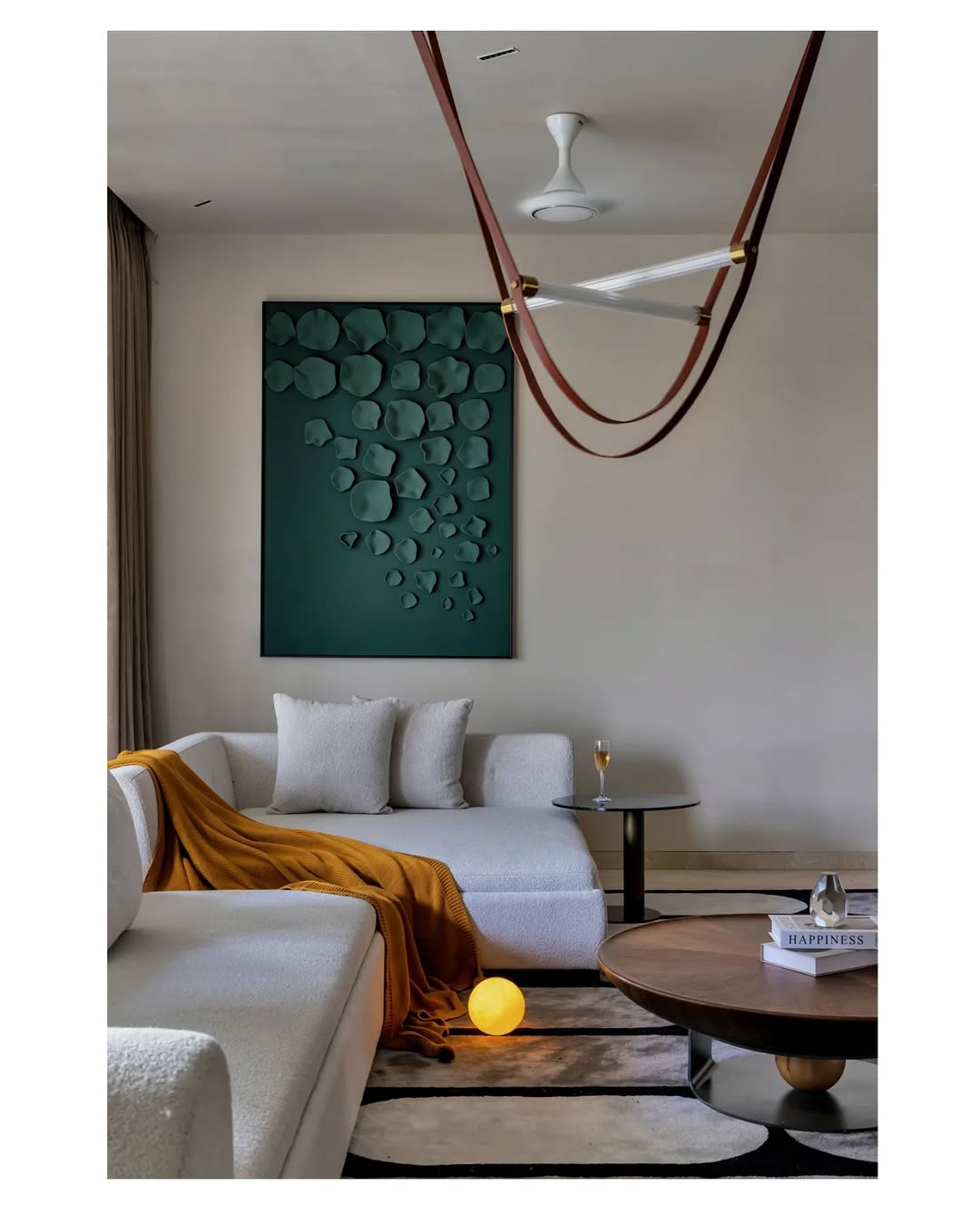 Modern living room with a white sofa, green wall art, and round coffee table.