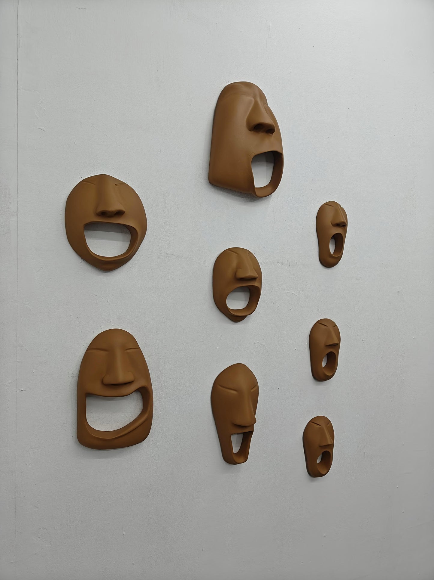 Set of brown ceramic face masks on a white wall
