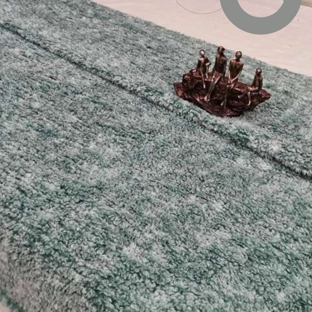 Small bronze sculpture of people on a textured green surface