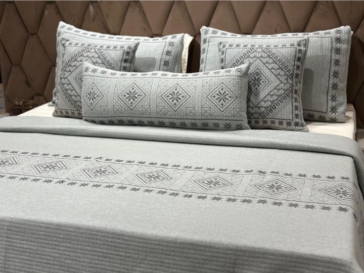 Gray patterned bedding set on a bed with a brown textured headboard.