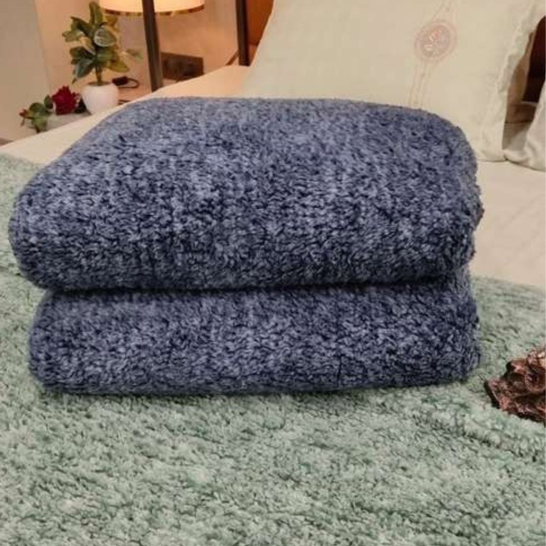 Two blue towels stacked on a green surface with a blurred indoor background