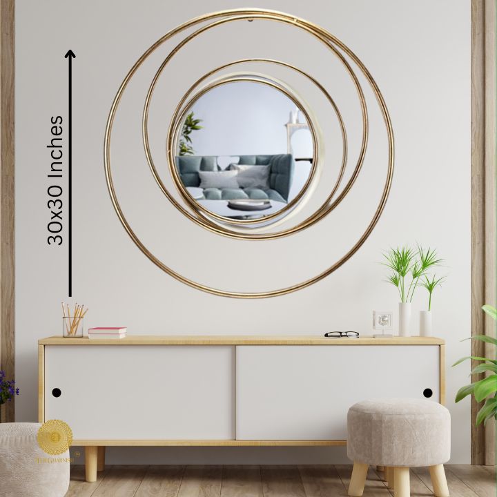Round metallic wall mirror with a ring of rings design, 30-inch diameter, by The Gharnish, hanging on a wall.