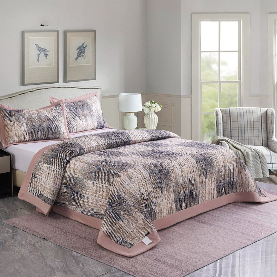 Bedroom with a patterned quilt on a bed, lamp, and chair.