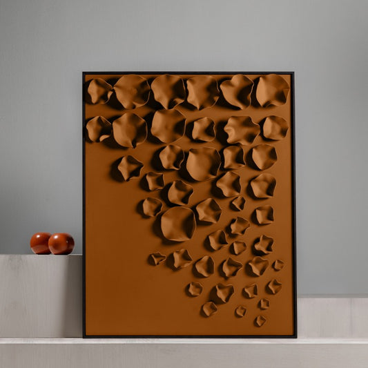 Brown textured wall art piece on a gray wall with two small brown sculptures.