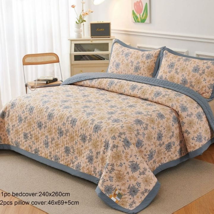 Floral bedspread with blue trim on a bed in a bedroom setting.