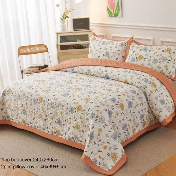 Floral bedspread set with matching pillows on a bed in a bedroom.