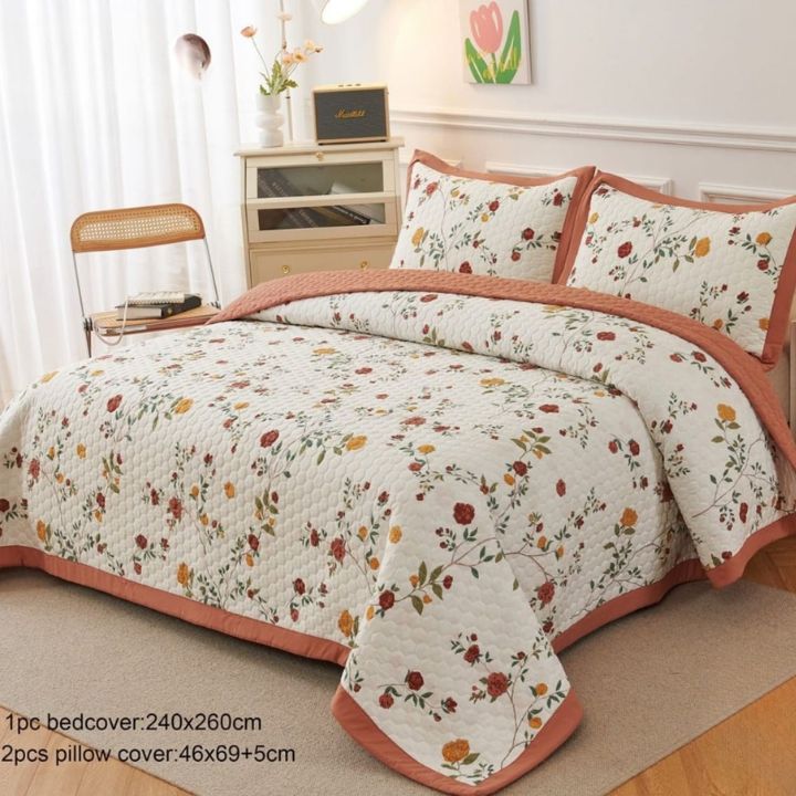 Floral bedspread set with matching pillows on a bed in a bedroom.