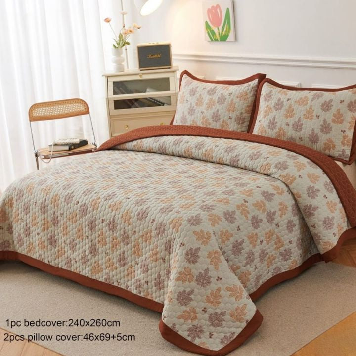 Floral bedspread set with matching pillows on a bed in a bedroom setting.
