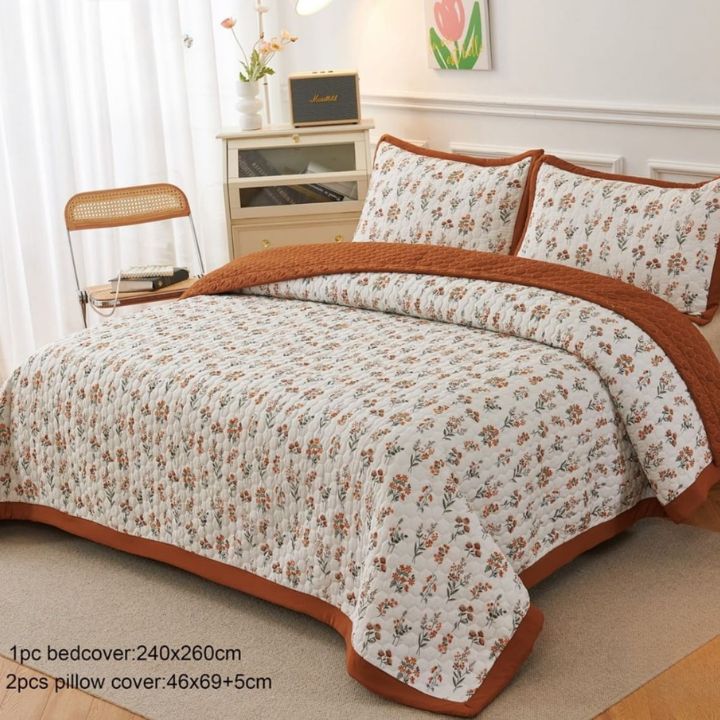 Floral bedspread with brown trim on a bed in a bedroom setting.