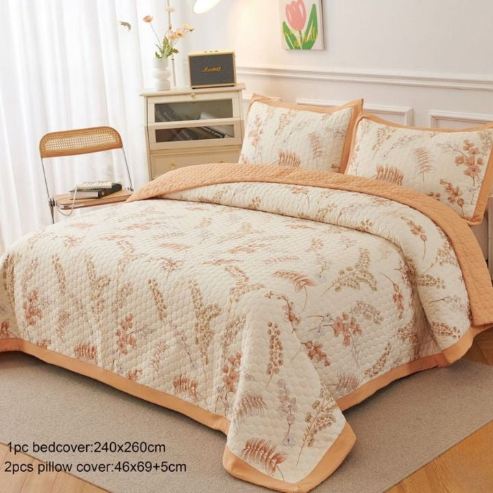 Floral patterned bedspread with matching pillows on a bed in a bedroom setting.