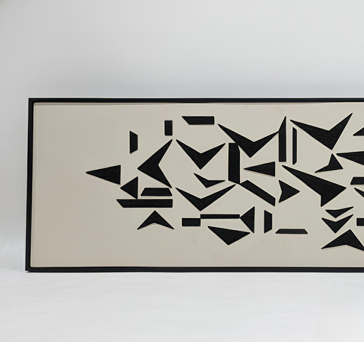 Framed abstract art with black geometric shapes on a beige background
