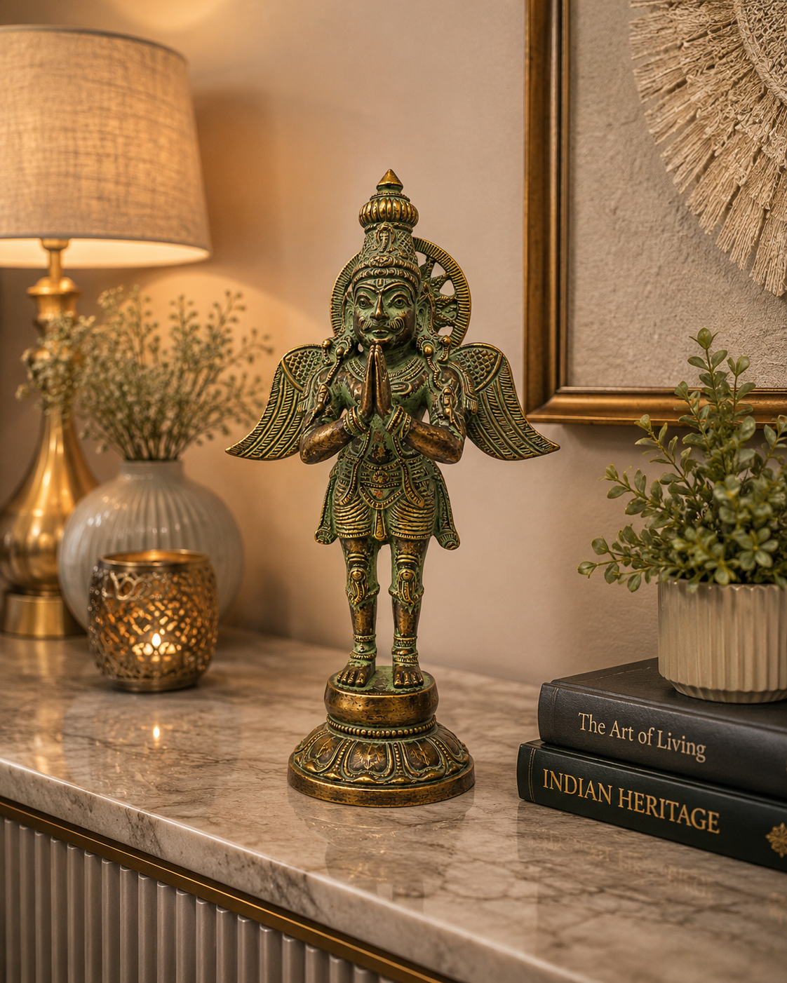 A small greenish-bronze statue of a standing deity with wings and a halo, displayed on a marble console table in a warmly lit room with a lamp, books, and plants.