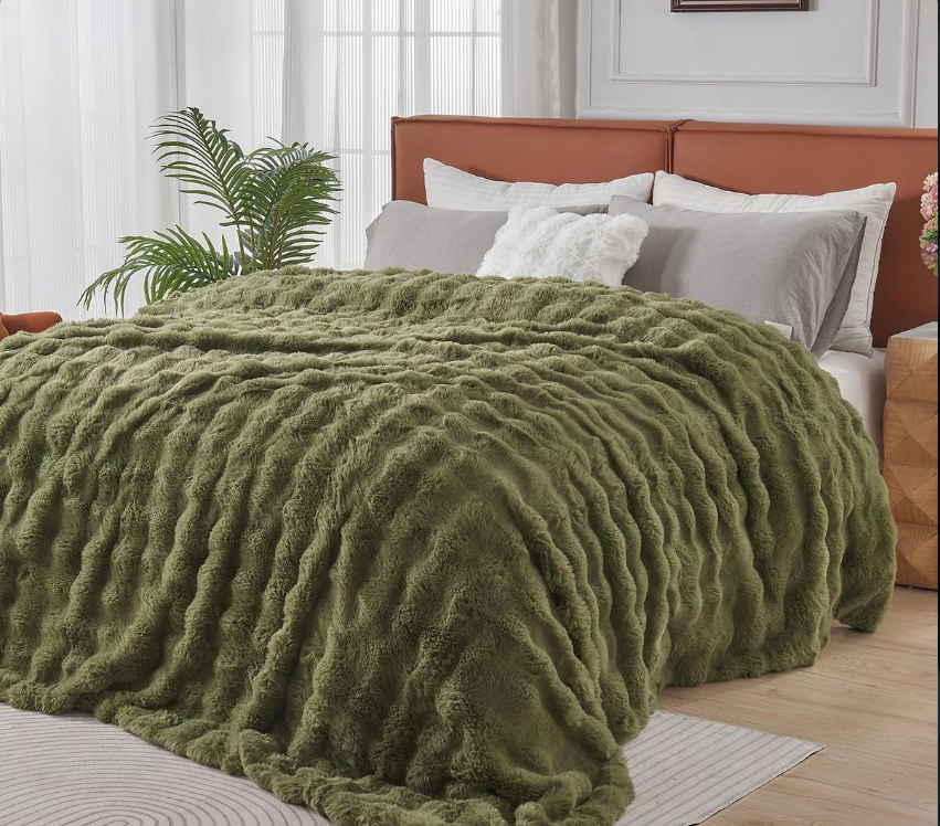 Green fuzzy blanket on a bed with a wooden headboard in a bedroom setting.