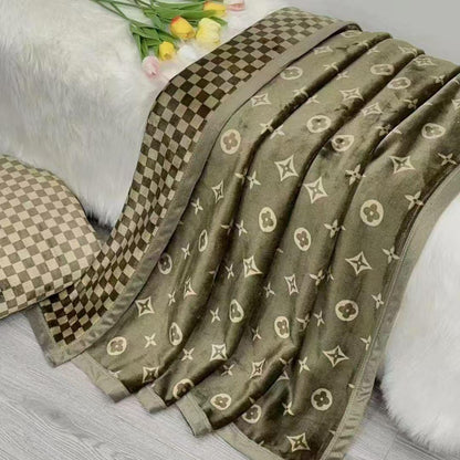 Green patterned blanket on a white surface with flowers in the background