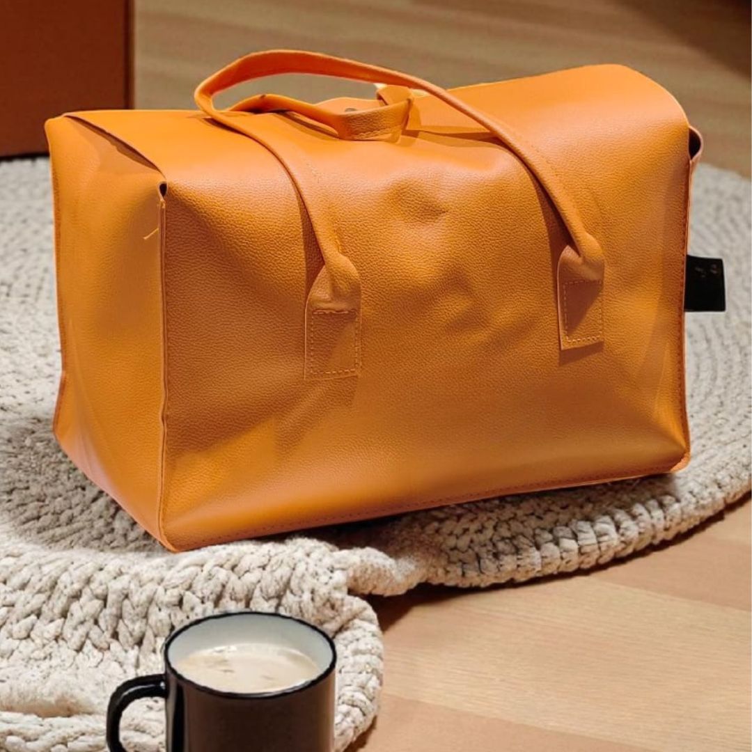 Orange leather bag on a textured surface with a cup of coffee nearby