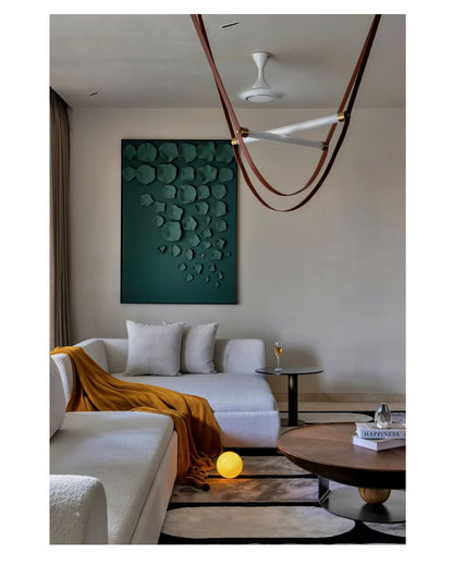 Modern living room with a white sofa, green wall art, and round coffee table.