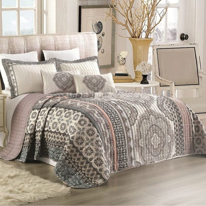 Patterned quilt on a bed in a bedroom setting with decor elements.