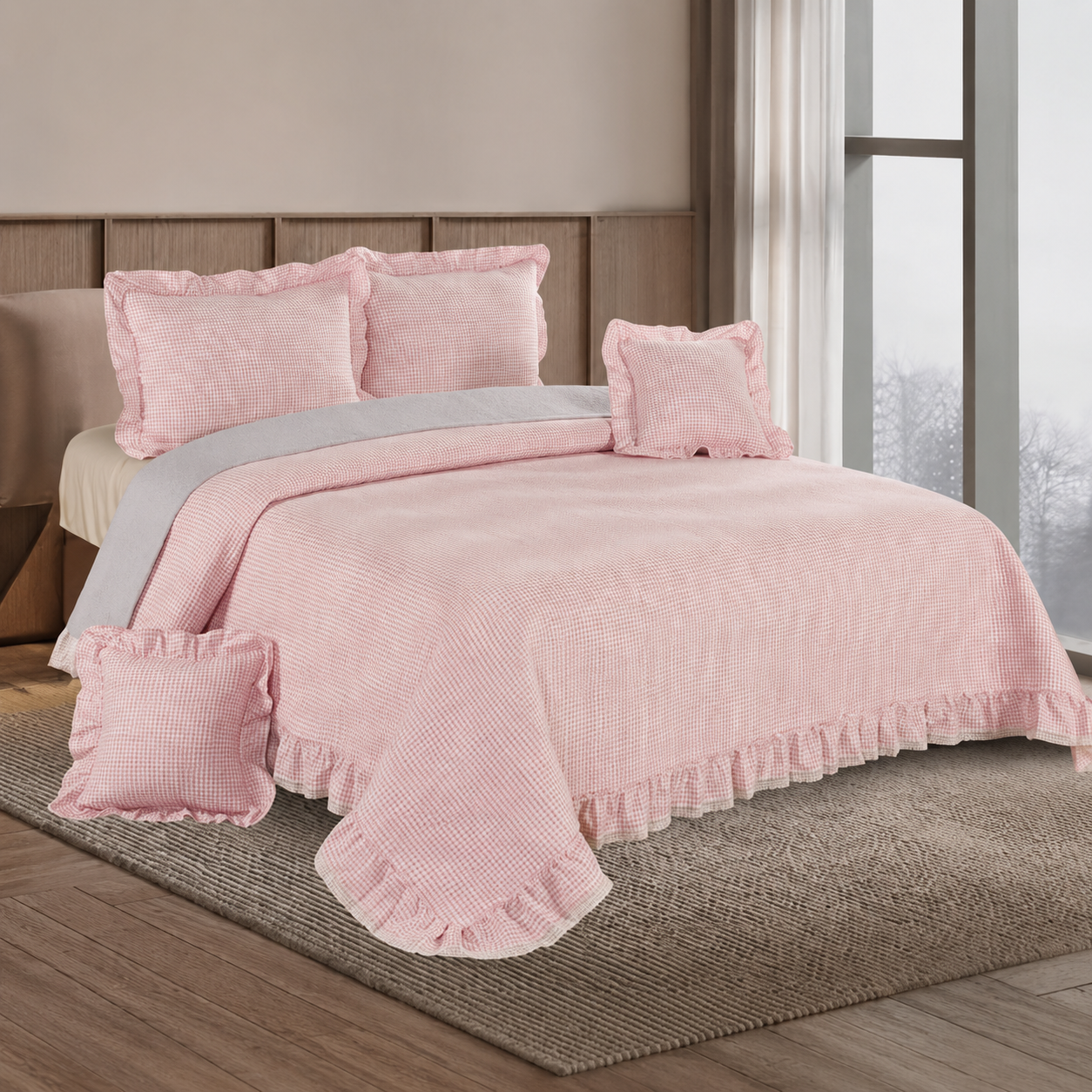 A pink textured quilted bedding set with ruffled edges and matching pillows, styled on a bed in a bedroom setting.
