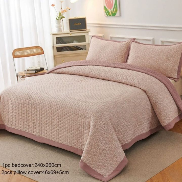 Pink quilt and pillow set on a bed in a bedroom setting