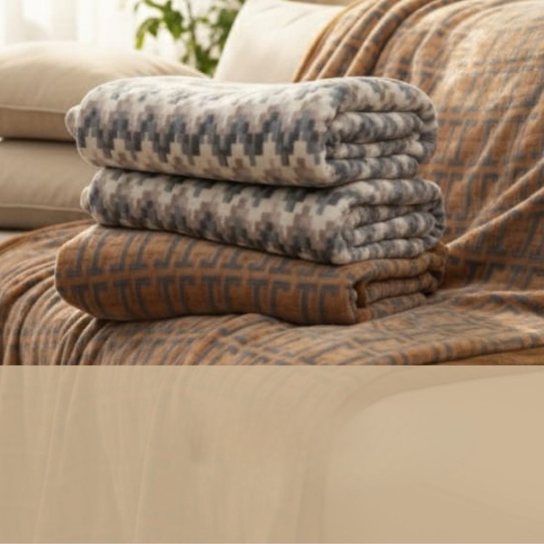 Stack of folded blankets on a couch with a neutral color scheme