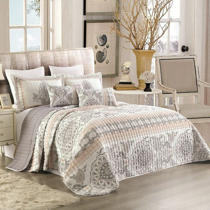 Bedroom with a patterned quilt on a bed, side table, and chair.