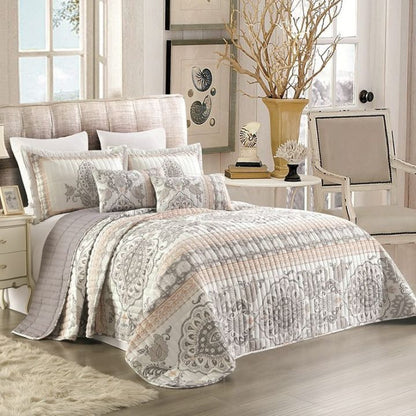 Bedroom with a patterned quilt on a bed, side table, and chair.