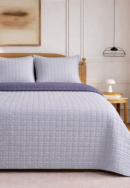 Soft and snug luxury 3-piece quilted bedding set by The Gharnish featuring a reversible pastel bedspread on a bed.