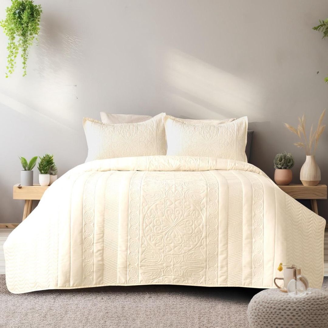 Beige quilted coverlet on a bed with pillows in a bedroom setting.