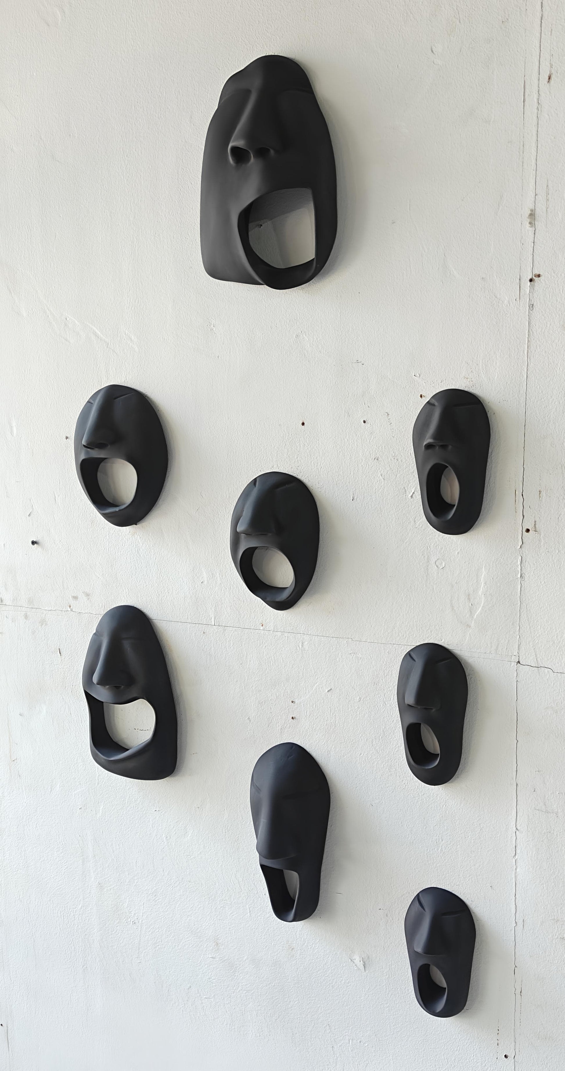 Set of black wall-mounted bottle openers on a white wall.