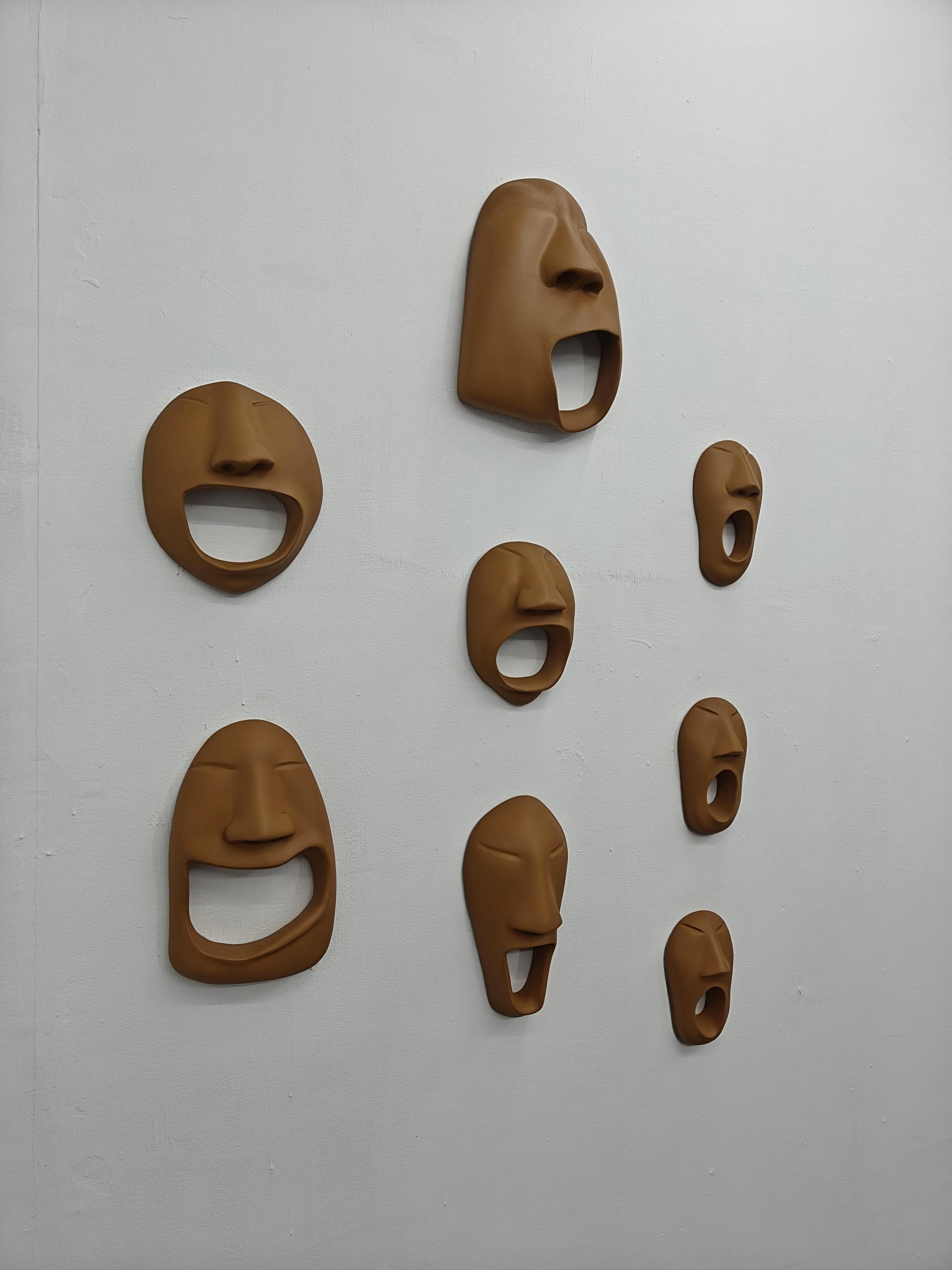 Set of brown ceramic face masks on a white wall