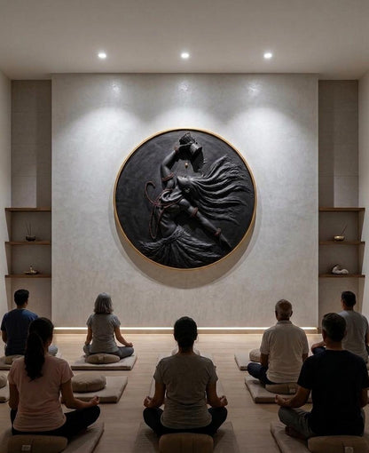 Group of people meditating in a room with a large wall sculpture.