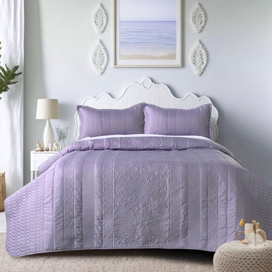 Purple quilt set on a bed in a bedroom with decorative elements.