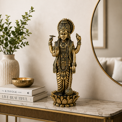 A detailed brass Lord Hanuman statue standing on a lotus base, displayed on a marble console table in a styled home interior next to a vase and books.