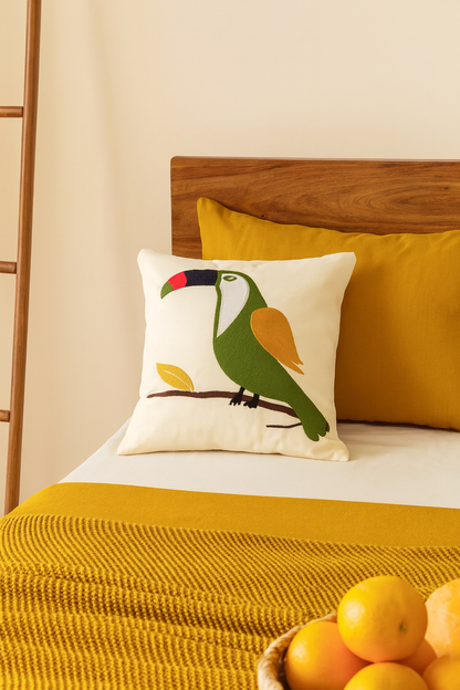 Decorative pillow with a toucan design on a bed with yellow and white bedding.
