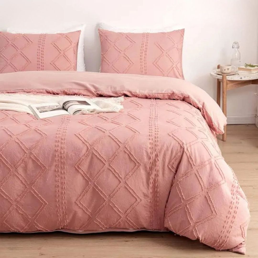 Pink textured duvet set on a bed with a side table in the background