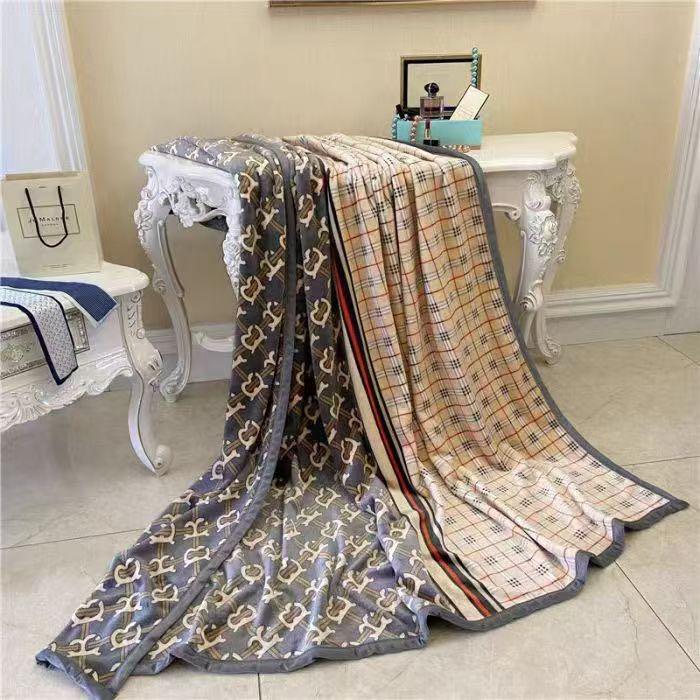 Two patterned blankets draped over a white table in a room with a beige wall.