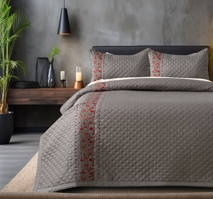 The Gharnish blush blossom quilted bedcover set featuring floral patterns and soft pastel colors on a neatly made bed.