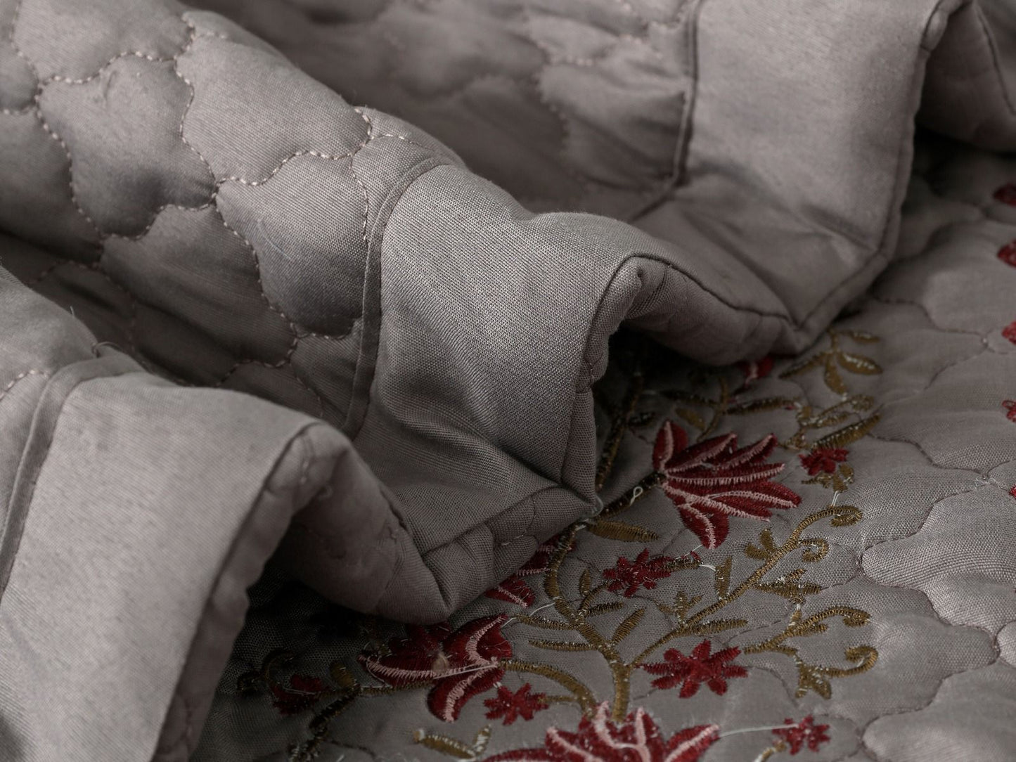 Blush Blossom quilted bedcover set by The Gharnish, featuring floral patterns and soft pastel colors for a cozy bedroom look.
