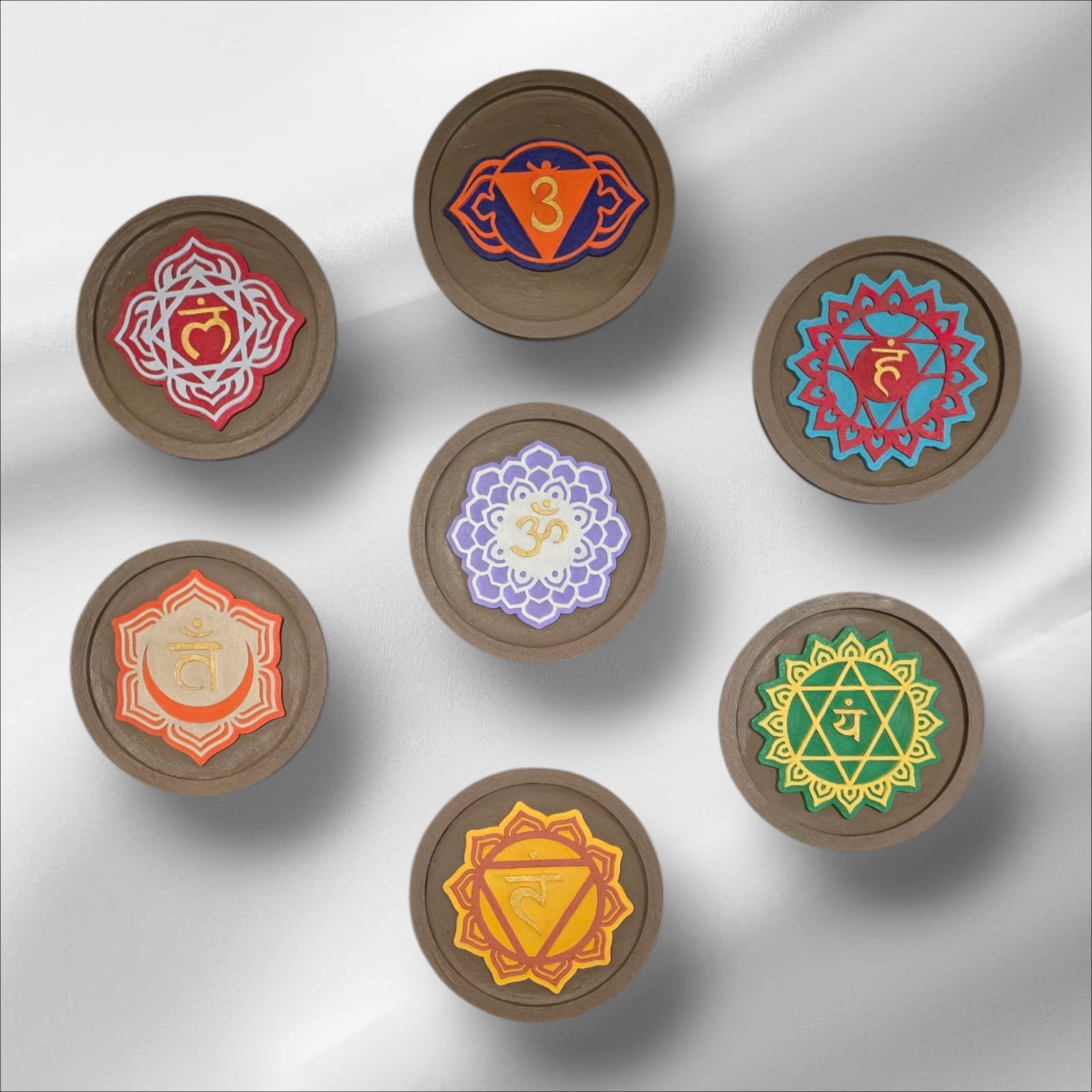 Set of seven wooden discs with colorful mandala designs on a white background