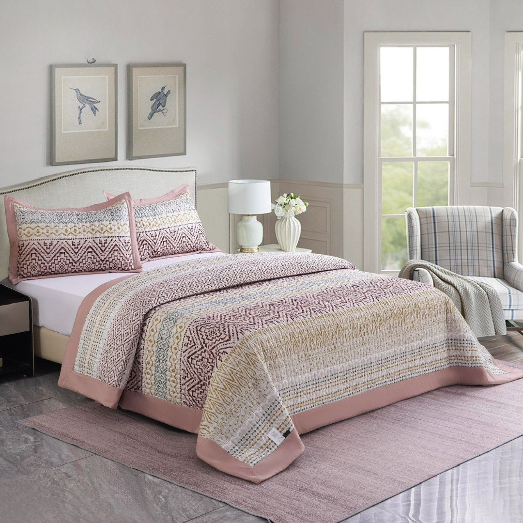 Bedroom with a bed covered in a patterned quilt and pillows, a lamp, and a chair.