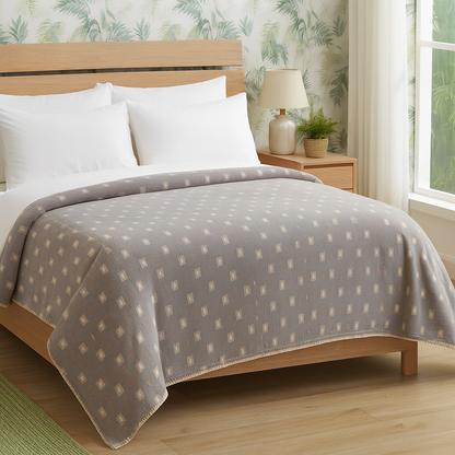 Bedroom with a bed covered by a gray patterned blanket, wooden headboard, and side table.