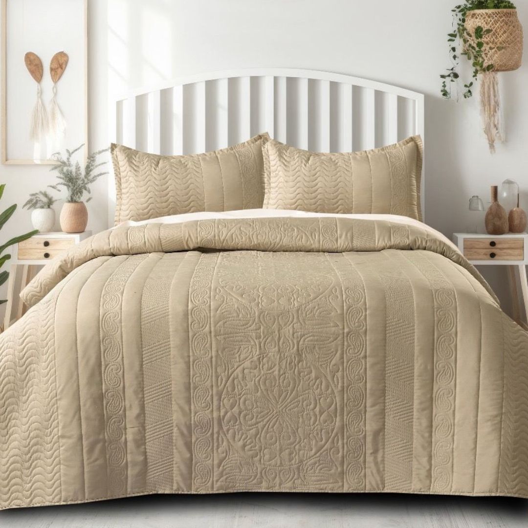 Beige quilt set on a bed in a bedroom setting with decor elements.