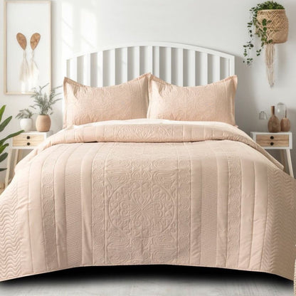 Beige quilt and pillow set on a bed in a bedroom setting with decor elements.