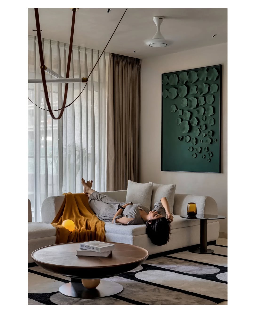 Person lying on a couch in a modern living room with a coffee table and decorative wall art.