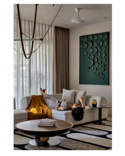 Person lying on a couch in a modern living room with a coffee table and decorative wall art.